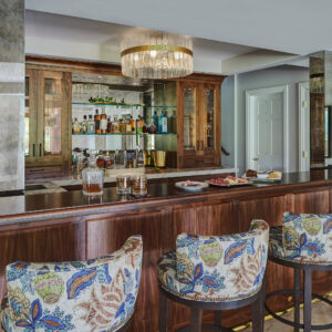 wood bar with custom wine stools and low profile glass and gold light fixture