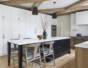 Modern Bohemian kitchen with black island, white countertops and seating on one end of the island